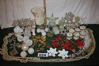 Wide view of assorted white, silver, and gold Christmas decorations including beads, snowflakes, star tree topper, spherical ornaments, and brass musical instruments with red yarn.