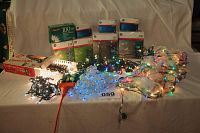 Eight boxes of new mini Christmas lights with various colors visible, loose blue and multicolored strings spread out