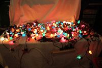 Full spread of multiple strings of large C-9 Christmas lights with multicolor bulbs lit and laid out on a surface.