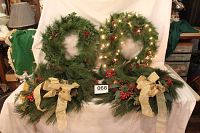 Four 22-inch pine needle wreaths displayed, two with gold bows and pine cones, two with string lights, one set of lights visibly on.