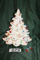 Front view of the vintage white ceramic Christmas tree adorned with multi-colored bulbs and showing gold-tipped branches, with extra bulbs placed next to it.