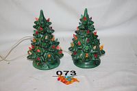 Pair of two green ceramic Christmas trees with multicolored light bulbs attached. Extra colored bulbs placed in front.