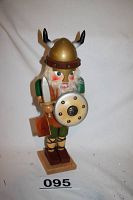 Full view of wooden Norseman Viking nutcracker standing on a wood base showing sword, shield, horned helmet, and attached tag.