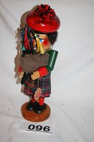 Full side view of the Steinbach Scottish bagpiper nutcracker standing on a wooden base with visible official tag.