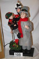 Side view of animated and illuminated Bob Cratchit holding Tiny Tim with lit street lamp, showing details of clothing and accessories