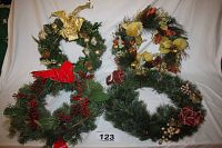 Four green decorative wreaths arranged together to show variety and size, decorated with gold, red, and berry accents.