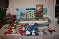 Full view of the gift wrapping supplies spread out on a table including rolls of paper, boxes, ribbons, bags, tissue, and assorted items.