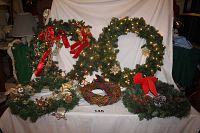 Overview of all five Christmas wreaths on display, showing two large lighted wreaths, three smaller unlit wreaths, and one twisted rope wreath with ribbons.