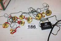 Overview of all 9 brass bells connected by electrical wires and adapter visible on a table.