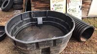 Top and side views of large black Rubbermaid agricultural water tub outdoors with dirt and tires in background.