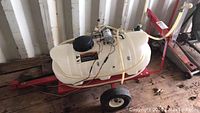 Sprayer mounted on red steel cart with plastic tank and wheels
