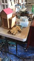 White folding table with bee house, gloves, and hardware on top showing condition and components