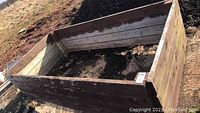 Wooden raised bed garden box viewed from the top angle, showing soil inside and weathered wood condition.