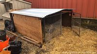 Side view of chicken run showing metal roof, wood panel side, and wire mesh.
