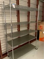 Full view of chrome metal shelving unit with six shelves on casters