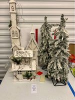 White wooden church and flocked trees on table against white wall, showing full lot contents