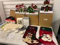 Full view of Christmas stockings, lighted paper houses, snowflake lights, and other decor arranged on shelves and boxes.