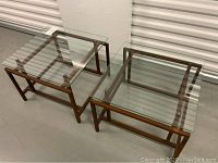 Two square wood-framed end tables with clear glass tops, shown side by side.