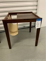 View of wooden Danish modern end table with canvas magazine sling from the front and side, showing the table's clean lines and sling attached.