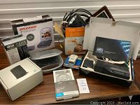 Full view of electronic items including DVD player box, various cords, ATT MicroCell box, Direct TV kit, and other devices.