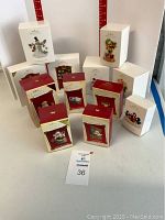 Several Hallmark Keepsake Ornaments in original boxes arranged on table, showing mainly white and red packaging with artwork of individual ornaments.