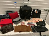 Photo showing Samsonite carry-on luggage, various travel toiletry and makeup bags, travel sonic toothbrush, Clairol curling iron, and other travel accessories arranged on a flat surface.