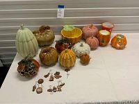 Full view of table showing all ceramic pumpkin decorations and metal ornaments.