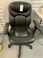 Front view of black office chair showing padded seat, back, headrest and arm rests