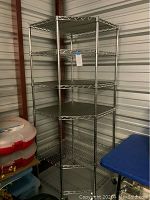 Full view of six-tier chrome wire corner shelving unit against metal wall