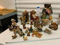 Overview of multiple Boyds Bears figurines, bookends and Lenox house on table with measuring tape