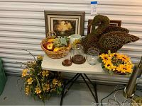 Overall view of the table showing the twine swan, framed art, pitchers, faux fruit basket, sunflower floral decor, and yellow floral arrangements.
