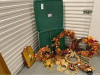 Photo of the autumn-themed wreaths, Thanksgiving wood wall hanging, and two Sterilite storage bins with green lids
