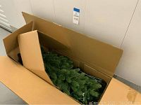 Open box showing green artificial pine branches inside box.