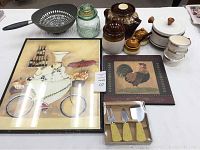 Overview of lot showing framed kitchen-themed artworks, enamel pot, small crock, condiment set, colander, glass jar with lid, nut bowls, and cheese knife set.