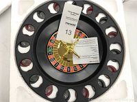 Top-down view of roulette wheel with shot glasses in slots, central spinner visible with attached papers
