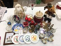Overview photo showing all items in the lot including plates, candles, jar, glass bowl with ornaments, plush Santa, and reindeer decoration.