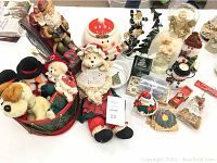 Overview of Christmas decorations including large Santa in sleigh, fabric angel doll, small candle holders, cookie jar, and other Christmas items on a table.