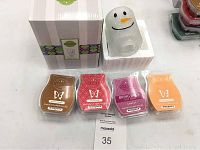 Photo showing the Frosty Glow snowman wax warmer and four Scentsy wax bars in their packaging marked with their scents.