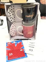 Boxed set of two Coco & Lola coffee mugs labeled 'naughty' (black) and 'nice' (pink) with matching coasters. The $25 Petro-Canada gift card placed in front of the box.