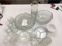 Photo showing the full lot with five platters, three candy plates, three bowls, one glass canister with lid, one candy dish with lid, and four glasses arranged on a white table.