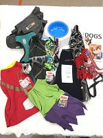 Full view of the dog lot showing all clothing, toys, collars, leads, harness, water bowl, and the dog book.