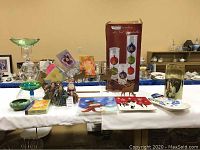 Full lot view showing decorative plates, card holder, Santa figurines, cards, and glassware on white table.