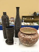 Full view of four decorative ceramic items on display including three vases and one planter, showing the different shapes and finishes.