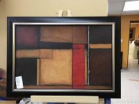 Full view of framed modern abstract art print with geometric block design in dark red, brown, tan, beige and black tones.