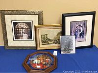 Five framed items displayed on a surface including prints and a decorative plate, shown together to establish lot contents