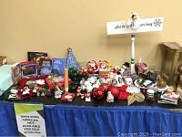 Full view of Christmas items on a black tablecloth including ornaments, stockings, and holiday decor