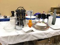 Wide view showing entire lot on table including spice rack, bowls, plates, vases, glasses, and serving tray.