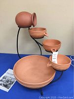 Full view of the cascade fountain showing four terracotta ceramic bowls on a black metal stand.
