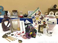 Overall display of various butterfly-themed home decor and jewelry items including sculpture, picture frame, vase, and fabric.