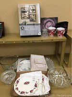 Photo of iron wall sconces box, mugs, floral plates, crystal bowls and wedding memory frame kit on shelf